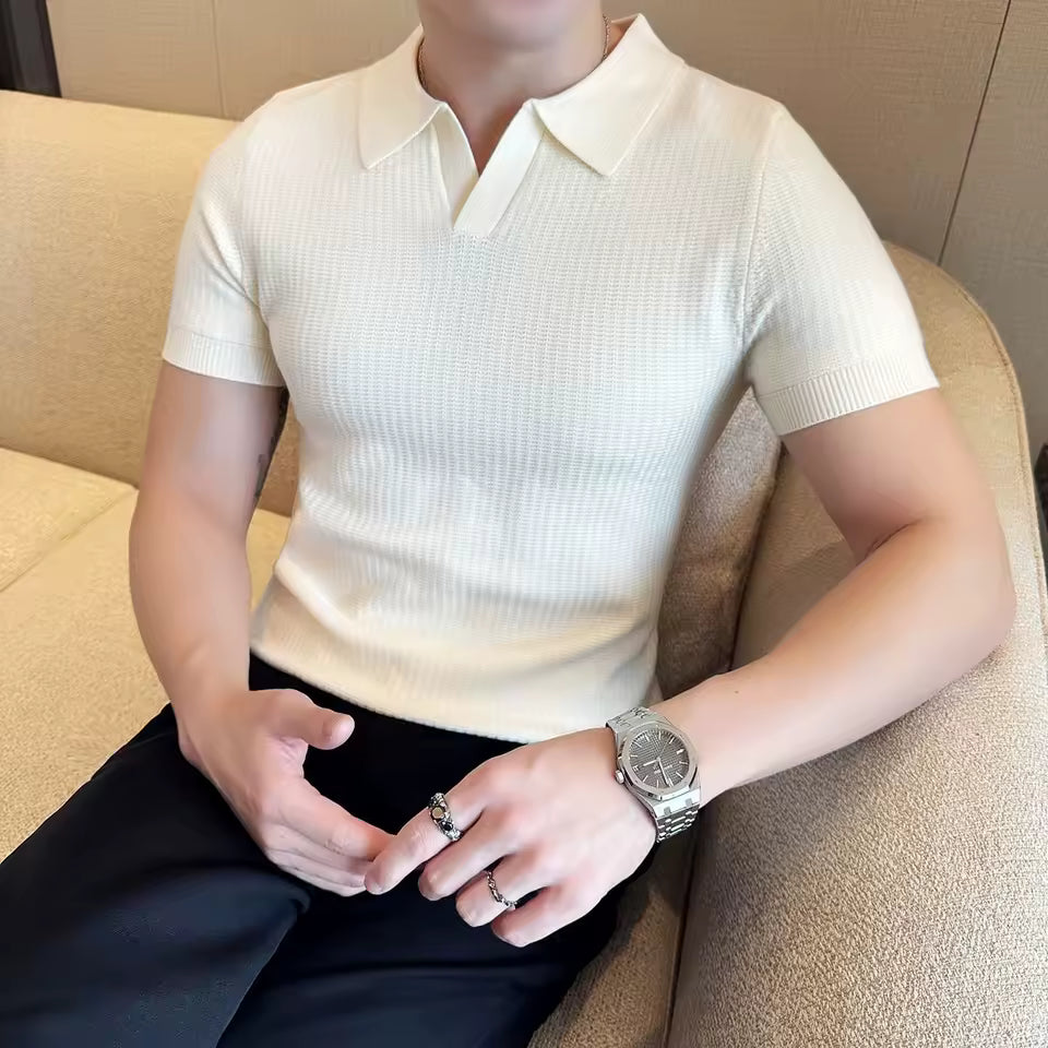 Person wearing a white short-sleeve knit polo shirt sitting on a beige couch.